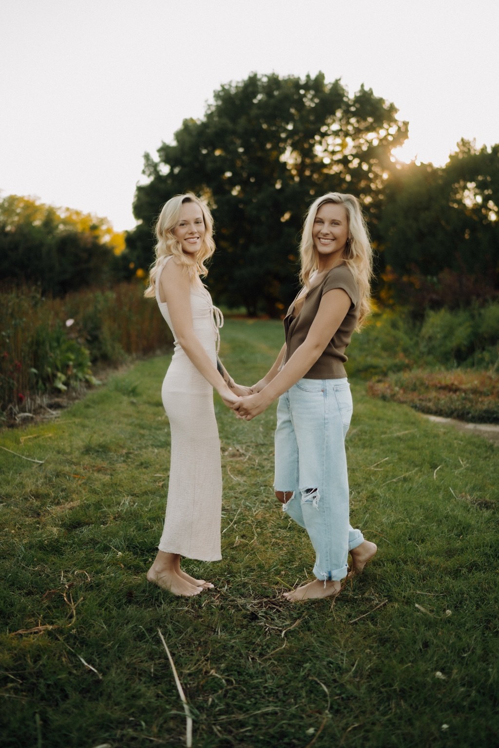 Two women holding hands in a sunlit garden
