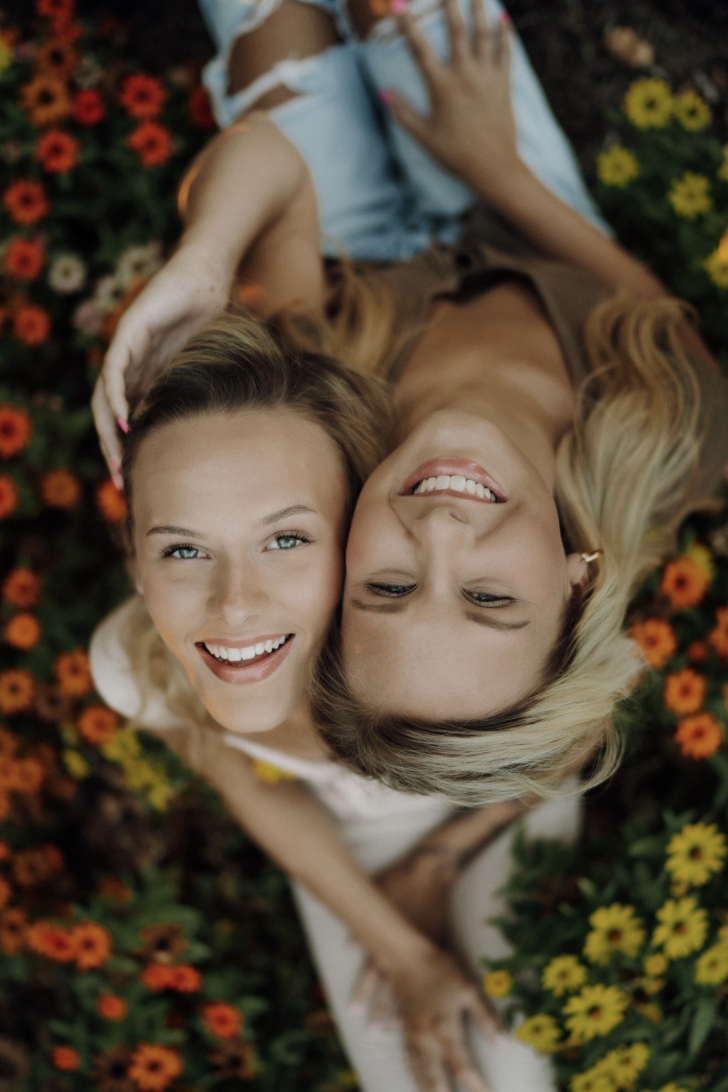 Two women smiling among garden flowers