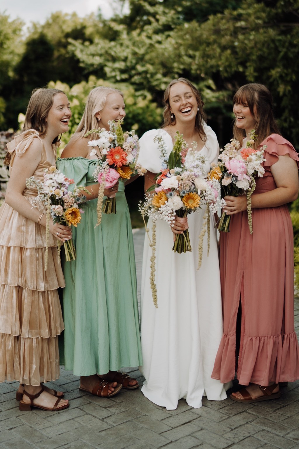Joyful bride and wedding party holding colorful bouquets