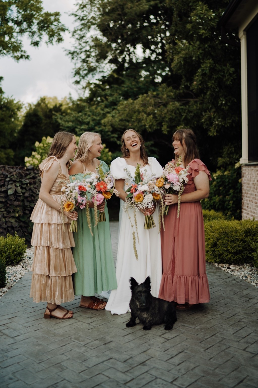 Bride and wedding party laughing together with bouquets and their dog
