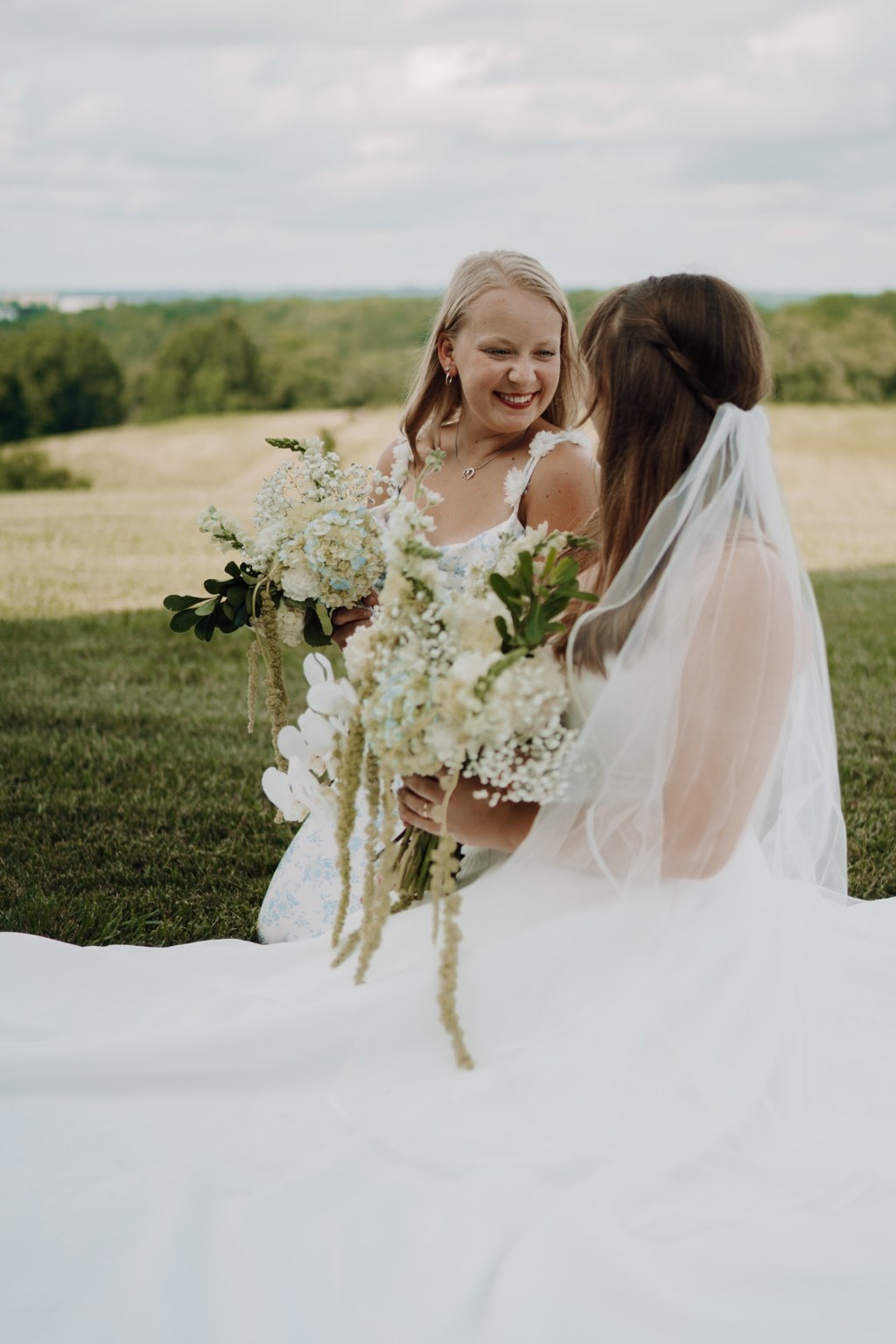 Two brides smiling together in an open field